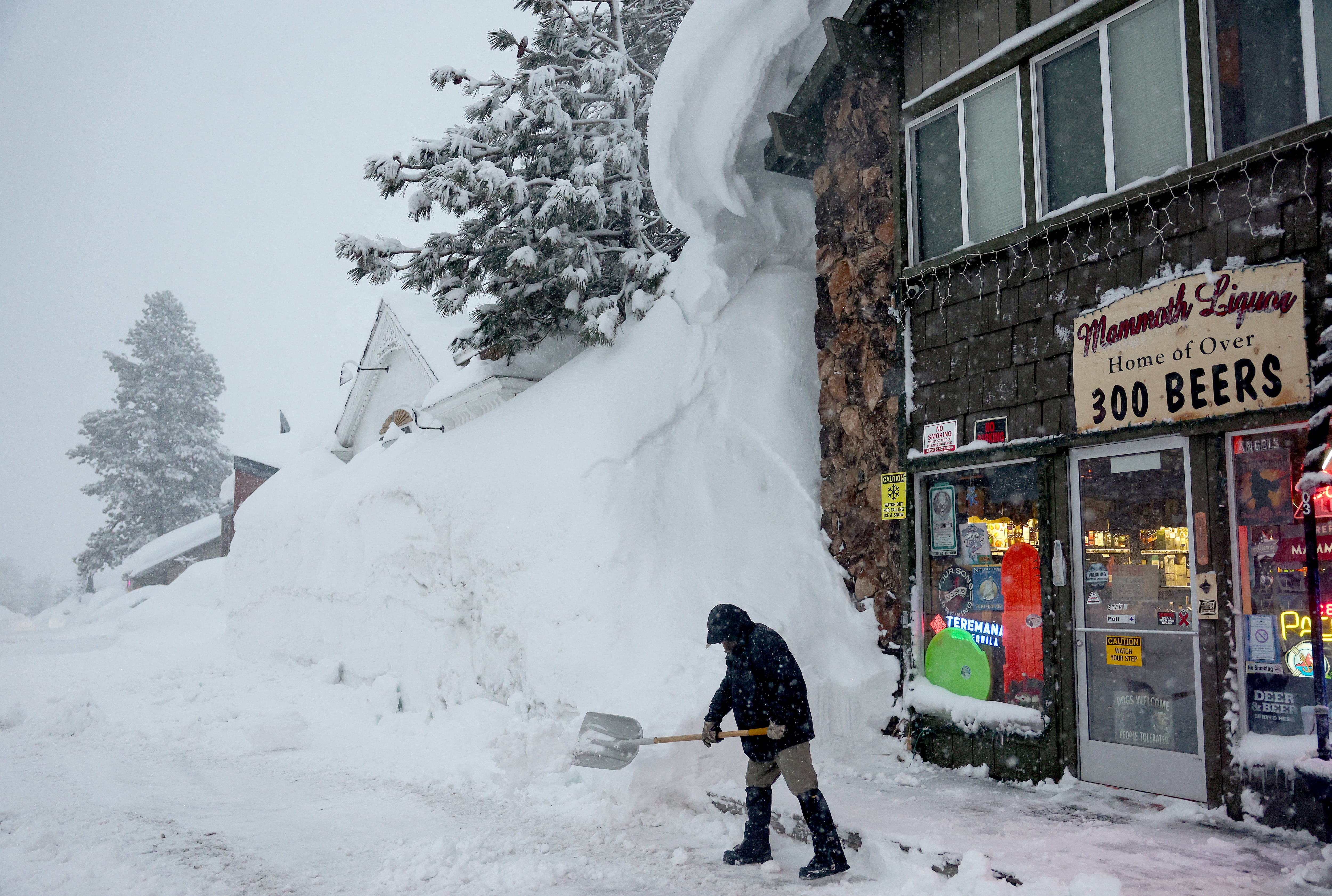 Spike Todd palas frente a su tienda cerca de bancos de nieve acumulados de tormentas anteriores durante otra tormenta de invierno en las montañas de Sierra Nevada el 10 de marzo de 2023 en Mammoth Lakes, California. Todd dijo: 'He vivido aquí 43 años y este se perfila como el invierno más grande que he visto en mi vida'. Las montañas de Sierra Nevada de California están siendo golpeadas por fuertes nevadas en elevaciones más altas, lo que eleva aún más los niveles de la enorme capa de nieve. Las comunidades de las montañas que aún se están recuperando de tormentas anteriores en elevaciones más bajas se enfrentan a posibles inundaciones debido a la escorrentía de lluvia de la décima tormenta fluvial atmosférica del estado. El presidente Joe Biden aprobó la solicitud de emergencia presidencial del gobernador Gavin Newsom en respuesta a las recientes tormentas que afectaron a California. Mario Tama/Getty Images/AFP (Foto de MARIO TAMA/GETTY IMAGES NORTH AMERICA/Getty Images vía AFP)