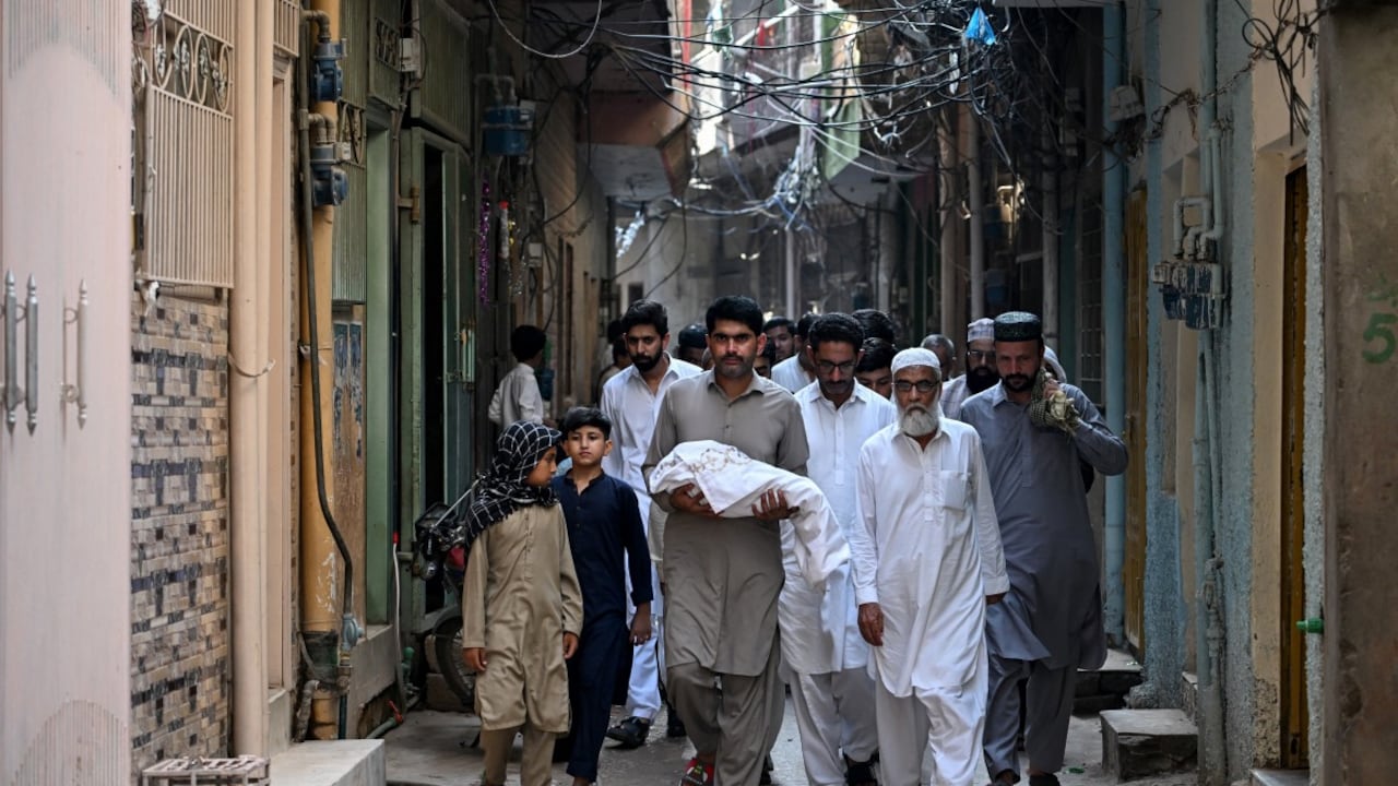 Un hombre carga el cuerpo de un recién nacido que falleció tras un incendio en la sala de maternidad del Instituto Pakistaní de Ciencias Médicas.
