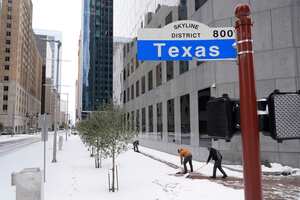 La gente quita la nieve de la acera con una pala el martes 21 de enero de 2025 en el centro de Houston. (Foto AP/Ashley Landis)
