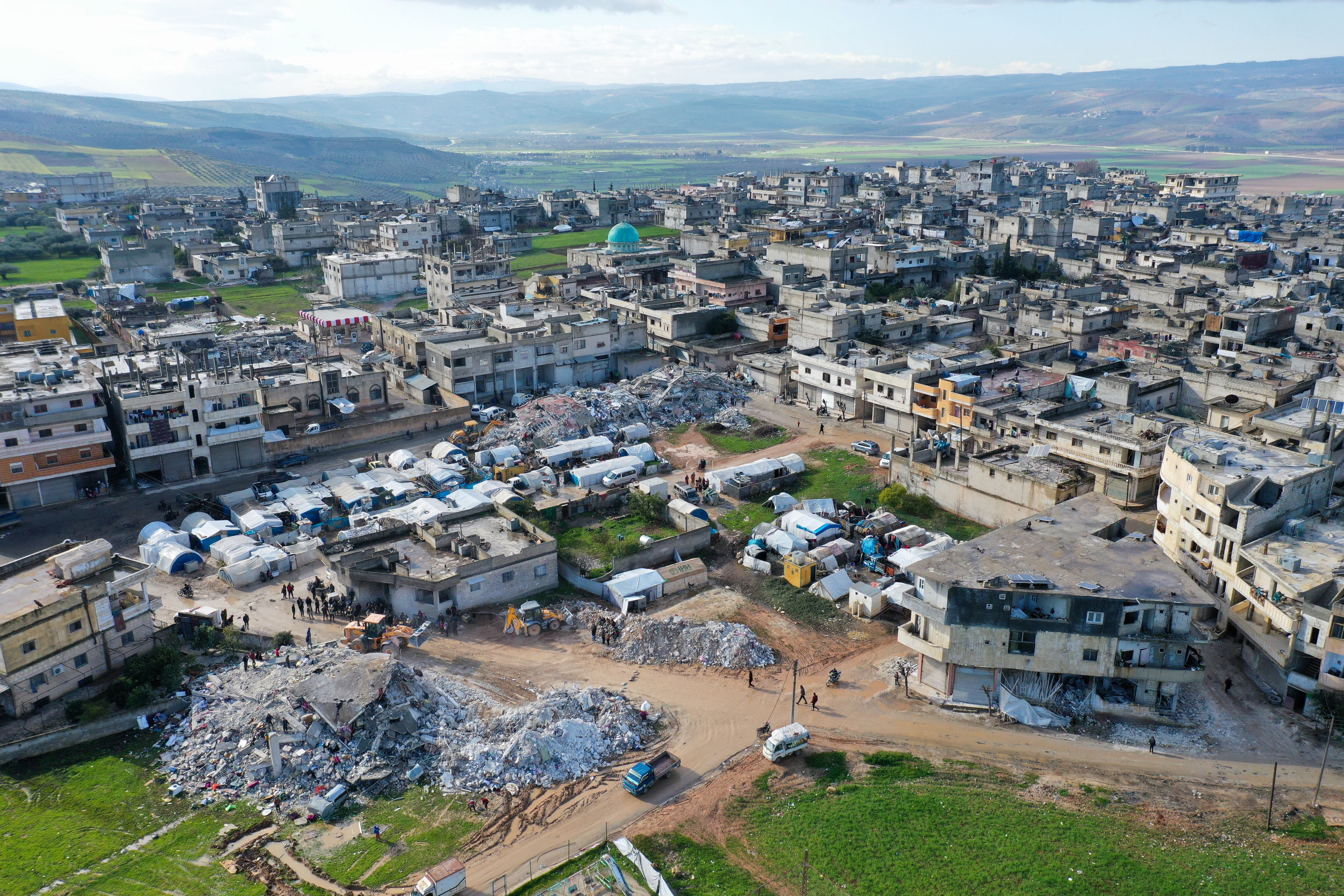 An aerial picture shows rescuers searching the rubble of buildings for casualties and survivors in the village of Azmarin in Syria's rebel-held northwestern Idlib province at the border with Turkey following an earthquake, on February 7, 2023. (Photo by Omar HAJ KADOUR / AFP)