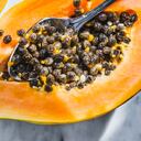 Papaya fruit cut in half with seeds on white marble background and sunbeam.