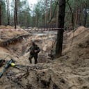 Un militar ucraniano usa un detector de metales para inspeccionar una fosa común en el área recientemente recuperada de Izium, Ucrania, el jueves 15 de septiembre de 2022, que contiene soldados ucranianos que murieron durante los combates contra los rusos cerca del comienzo de la guerra. (AP Photo/Evgeniy Maloletka)