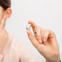 Solución auditiva para niños. Niña sosteniendo un audífono, tratamiento de la sordera en niños. Audiología