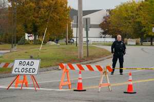 Un oficial de policía se encuentra en un cierre de carretera cerca de una bolera, visto al fondo, el jueves 26 de octubre de 2023, en Lewiston, Maine.