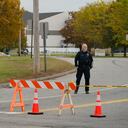 Un oficial de policía se encuentra en un cierre de carretera cerca de una bolera, visto al fondo, el jueves 26 de octubre de 2023, en Lewiston, Maine.