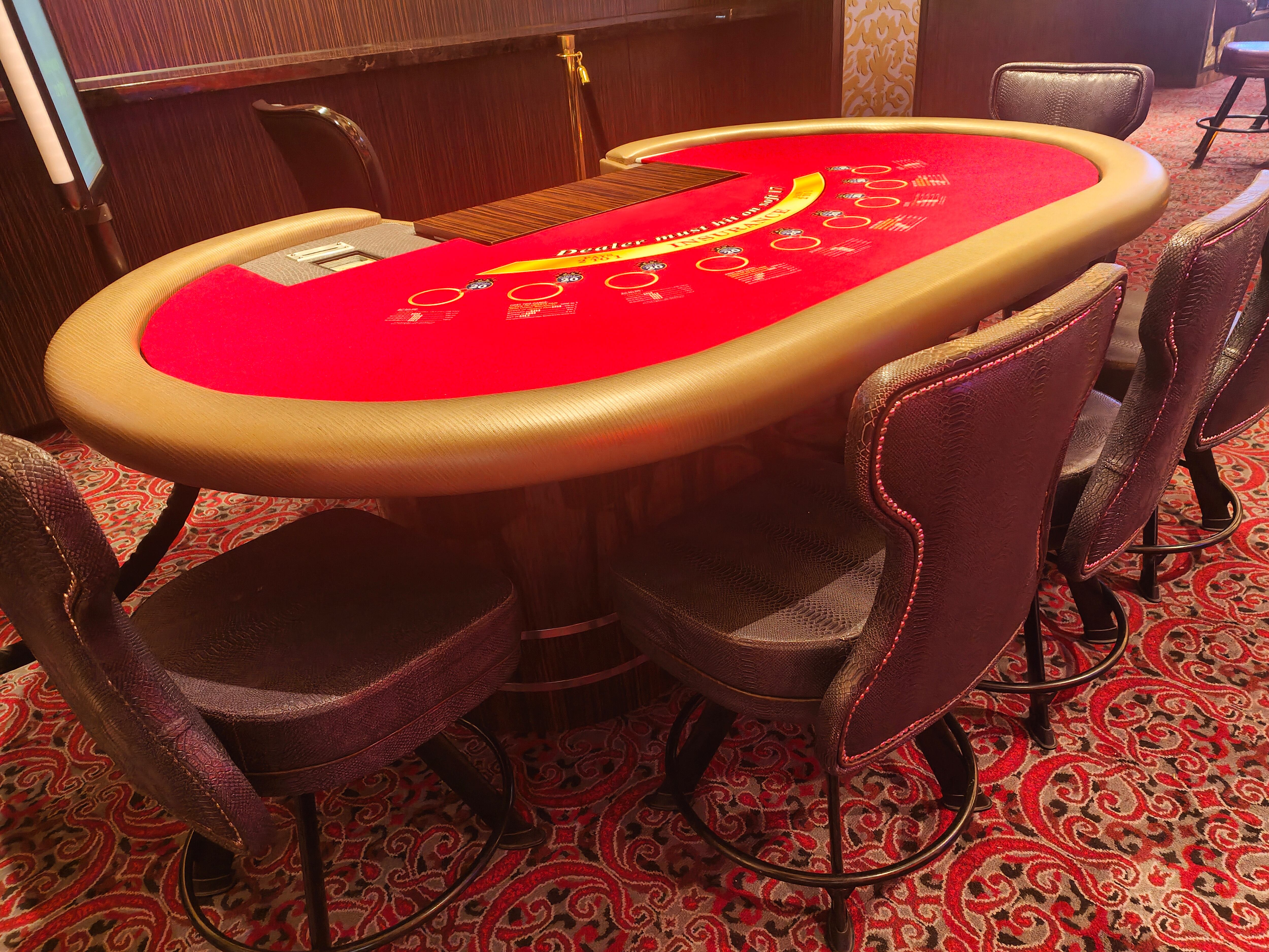 Primer plano de una mesa y sillas de juego de blackjack rojas en casino de Singapur