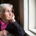 Anciana con gafas mirando pensativamente por la ventana.