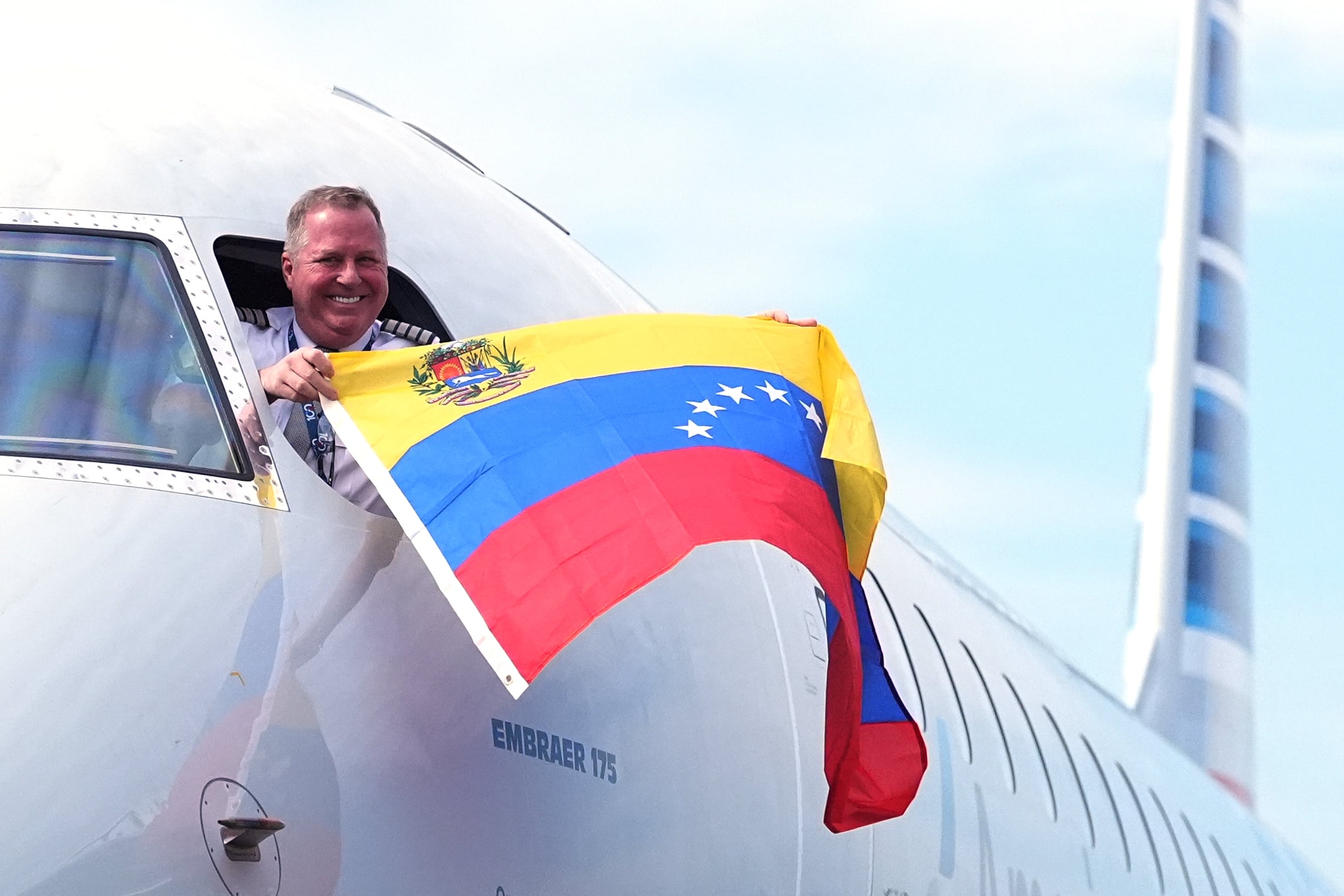 El capitán Ric Wilson ondea una bandera venezolana desde la ventanilla de la cabina mientras se prepara para pilotar el vuelo AA3599 de American Airlines, el primer vuelo comercial directo entre Estados Unidos y Venezuela.