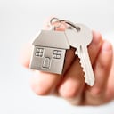 Sosteniendo las llaves de la casa en el concepto de llavero en forma de casa para comprar una casa nueva