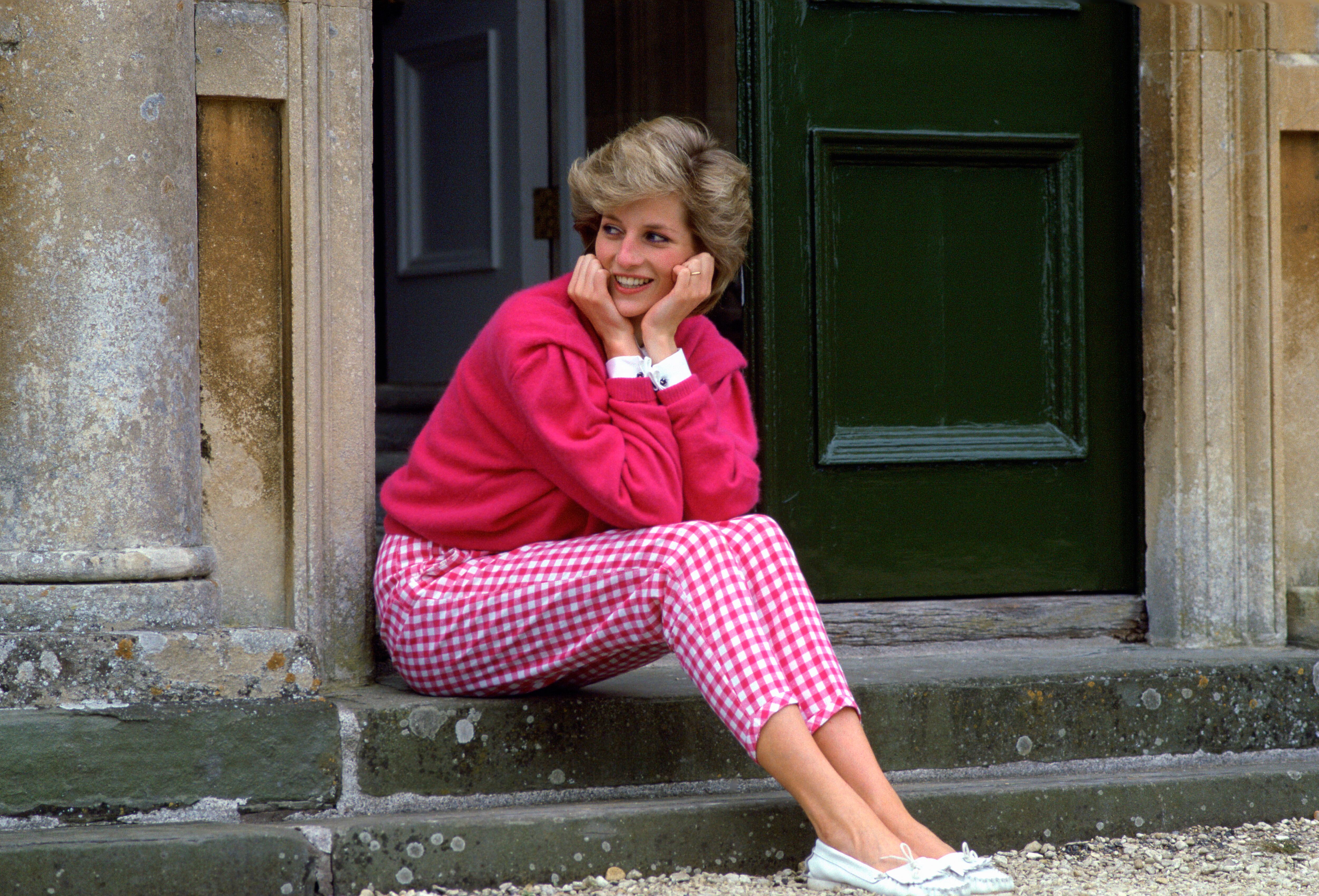 HIGHGROVE, UNITED KINGDOM - JULY 18: Diana, Princess Of Wales, Sitting On The Steps Outside Her Country Home, Highgrove. The Princess Is Casually Dressed In Pink Gingham Trousers With A Matching Pink Jumper. (Photo by Tim Graham Photo Library via Getty Images)