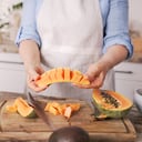Summer, fruit and woman with papaya in kitchen ready to make healthy snack, fruit salad and lunch at home. Nutrition, food and people cutting tropical fruit for vegetarian, vegan and healthy diet