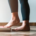 Hembra comprobando kilogramos subiendo a la báscula - concepto de autocuidado y positividad corporal - bengala cálida a la izquierda