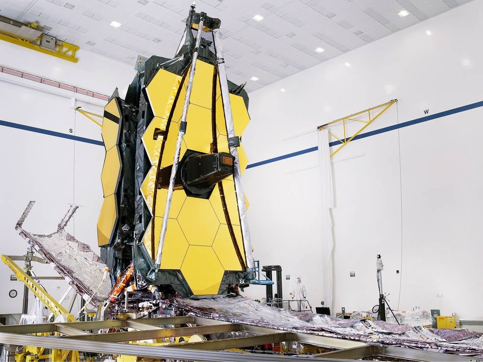 The fully assembled James Webb Space Telescope with its sunshield and unitized pallet structures (UPSs) that fold up around the telescope for launch, are seen partially deployed to an open configuration to enable telescope installation.
Credits: NASA/Chris Gunn
