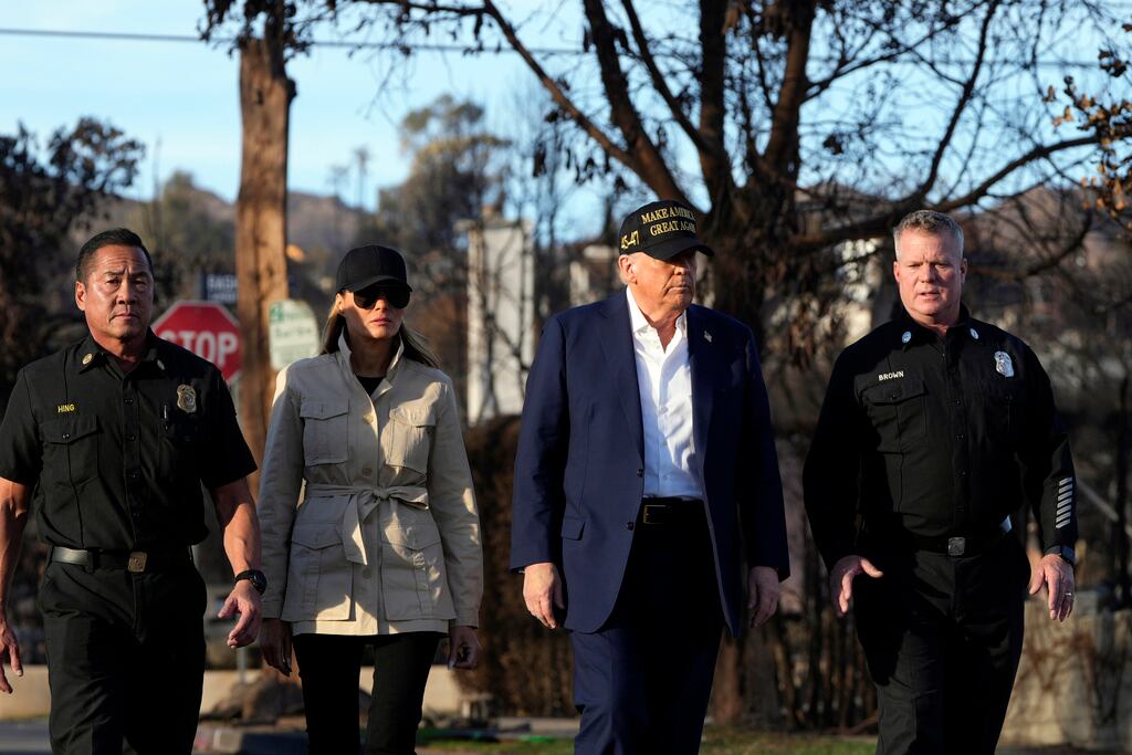 El presidente Donald Trump y la primera dama Melania Trump caminan con Jason Hing, jefe adjunto de los servicios de emergencia del Departamento de Bomberos de Los Ángeles, izquierda, y el capitán Jeff Brown, jefe de la Estación 69, mientras recorren el vecindario de Pacific Palisades afectado por los recientes incendios forestales en Los Ángeles, viernes 24 de enero de 2025. (Foto AP/Mark Schiefelbein)
