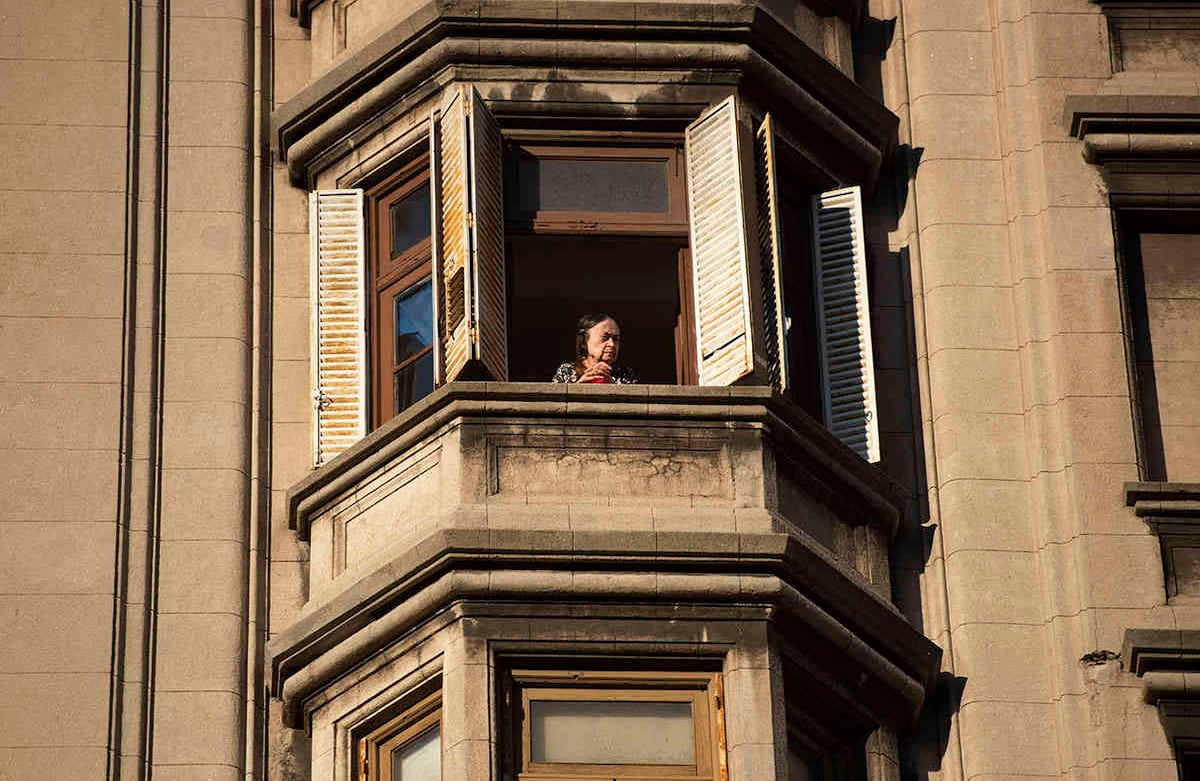 Una anciana mira desde su ventana el edificio del Palacio Salvo en Montevideo, Uruguay. (Foto AP / Matilde Campodonico)