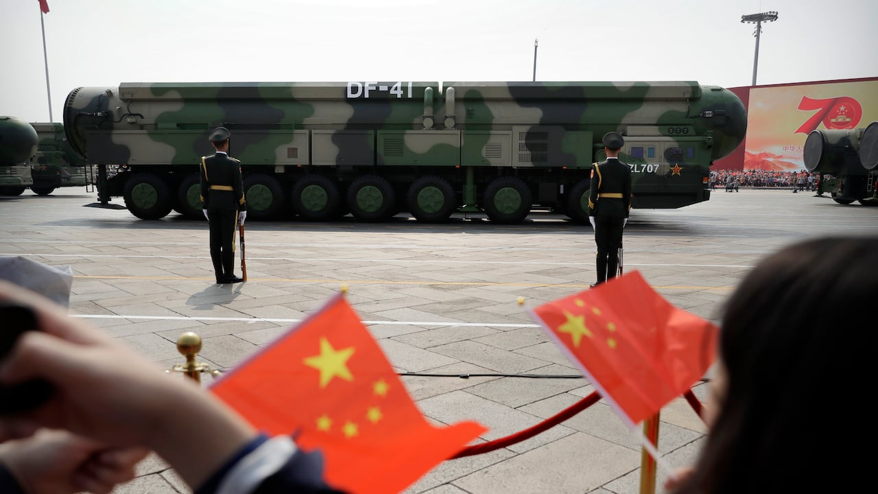 Espectadores ondean banderitas chinas mientras vehículos militares con misiles balísticos DF-41 pasan durante un desfile en ocasión del 70mo aniversario de la fundación del Partuido Comunista de China en Beijing. (AP Foto/Mark Schiefelbein)
