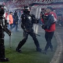 Momento en el que las unidades de seguridad retiran del campo de juego a los hinchas de Santa Fe tras los enfrentamiento con la barra del América.