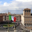 Roma, Italia. Una gran bandera italiana ondea sobre el monumento Altar de la Patria, también conocido como Vittoriano, frente a la Piazza Venezia en un día soleado