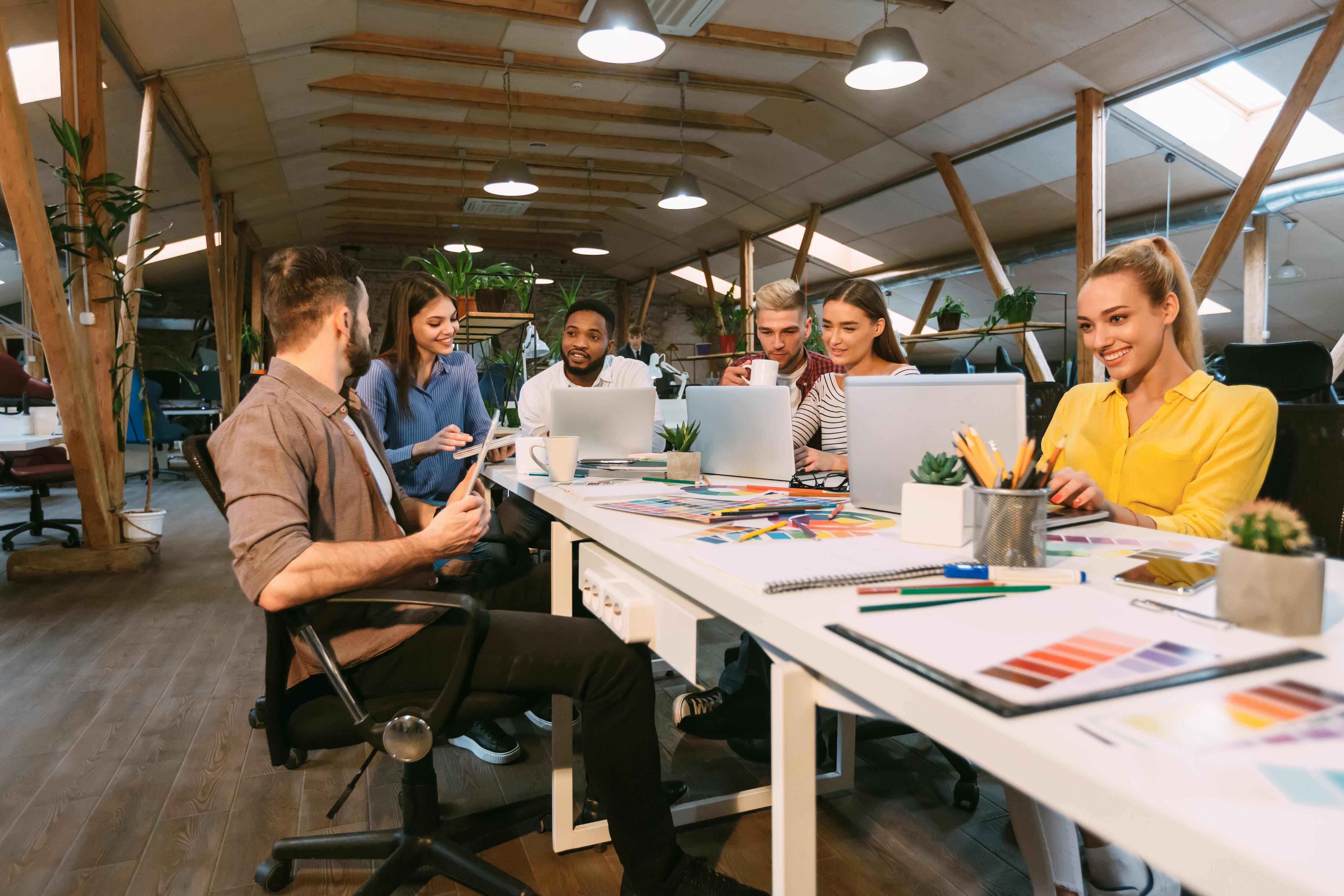 Jóvenes diseñadores que trabajan con el proyecto, discutiendo el desarrollo de nuevos pedidos en la oficina moderna
