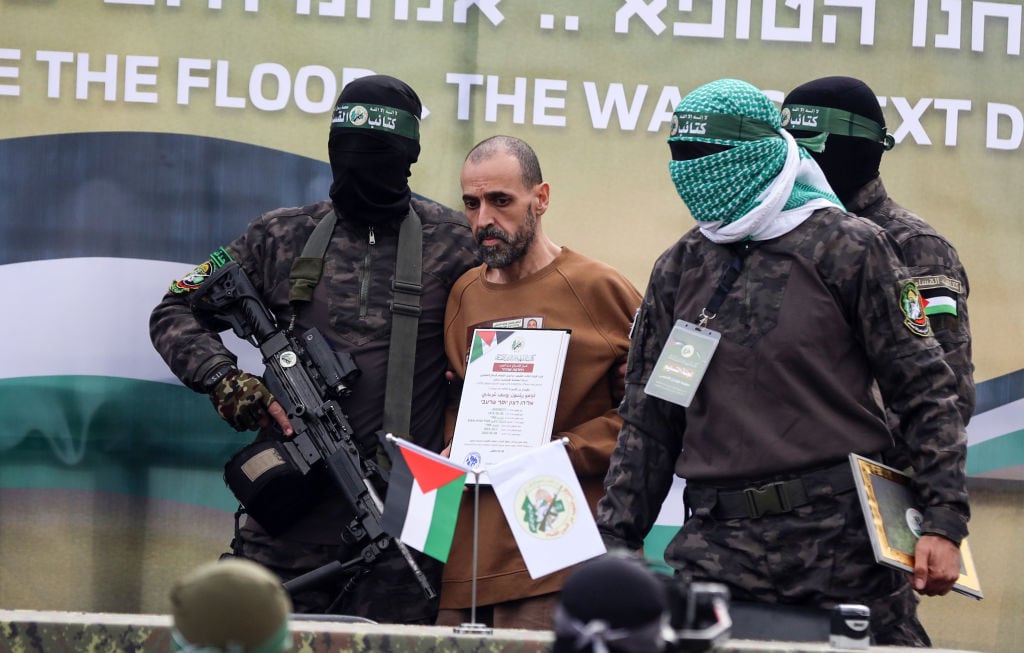 Palestinian Hamas fighters escort Israeli hostages before handing them over to a Red Cross team in Deir el-Balah, central Gaza, on February 8, 2025, as part of the fifth hostage-prisoner exchange of a fragile ceasefire. The swap comes after US President Donald Trump proposes clearing out the Gaza Strip of its inhabitants and for the United States to take over the Palestinian territory--a plan that sparks global uproar and is rejected by Hamas. (Photo by Majdi Fathi/NurPhoto via Getty Images)
