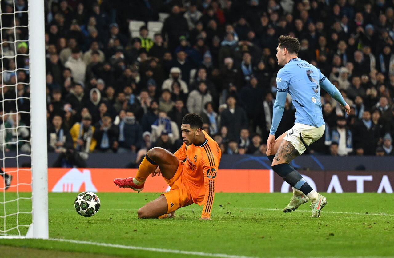 Jude Bellingham del Real Madrid marca el tercer gol de su equipo mientras está bajo la presión de John Stones del Manchester City durante el partido de ida de los octavos de final de la UEFA Champions League 2024/25 entre el Manchester City y el Real Madrid C.F. en el Manchester City Stadium el 11 de febrero de 2025 en Manchester, Inglaterra.