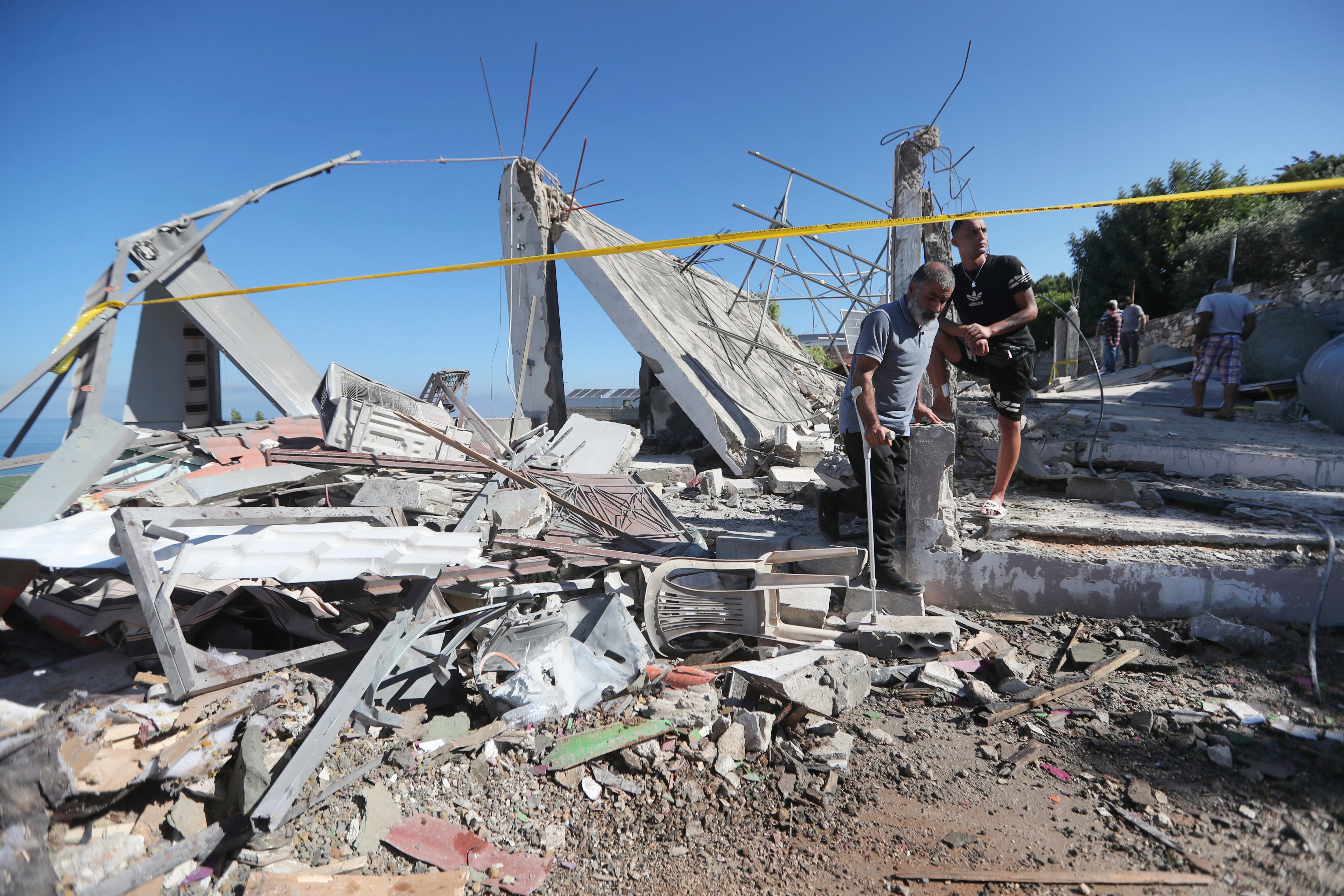 Hombres libaneses inspeccionan una casa destruida que fue alcanzada el viernes por la noche por un ataque aéreo israelí, matando a una mujer e hiriendo a varias personas más, en la aldea sureña de Adloun, Líbano, el sábado 1 de junio de 2024.