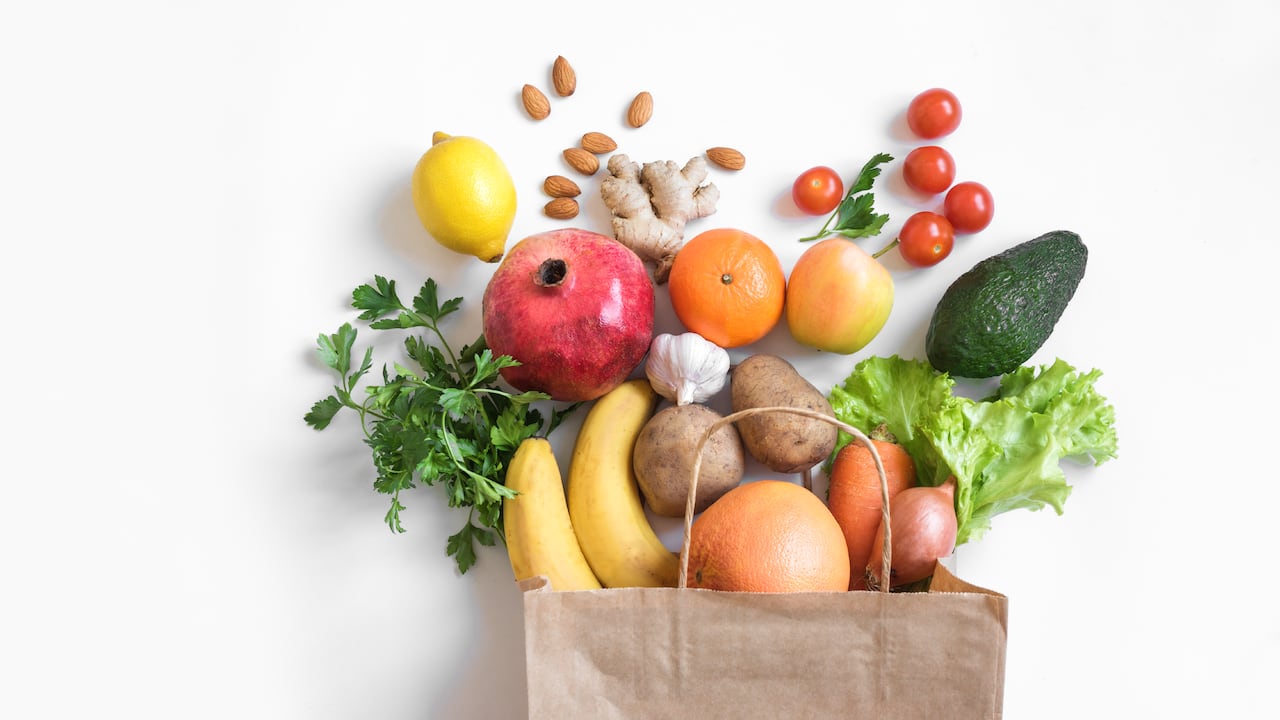 Fondo de alimentos saludables. Comida vegetariana vegana saludable en verduras y frutas de bolsa de papel en blanco, espacio de copia, banner. Supermercado de alimentos de compras y concepto de alimentación vegana limpia.