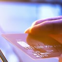 Hombre que usa su tarjeta de crédito en línea para comprar y realizar operaciones bancarias con la luz del sol entrando por la ventana