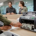Bank teller using cash counting machine in bank branch