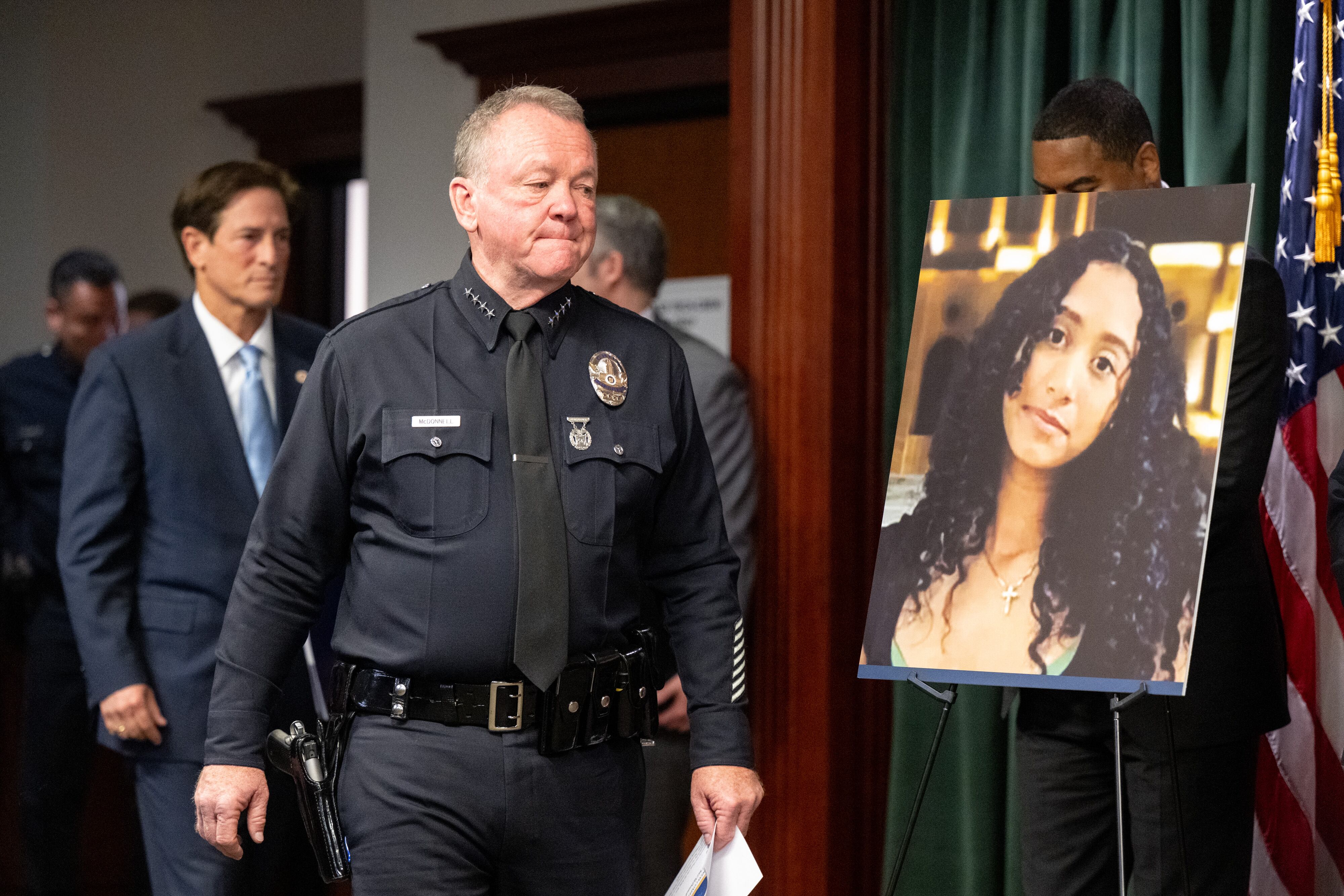 El jefe de policía de Los Ángeles, Jim McDonnell, y el fiscal de distrito de Los Ángeles, Nathan Hochman, pasan junto a una fotografía de Celeste Rivas Hernández, de 14 años y residente de Lake Elsinore, el lunes 20 de abril de 2026.