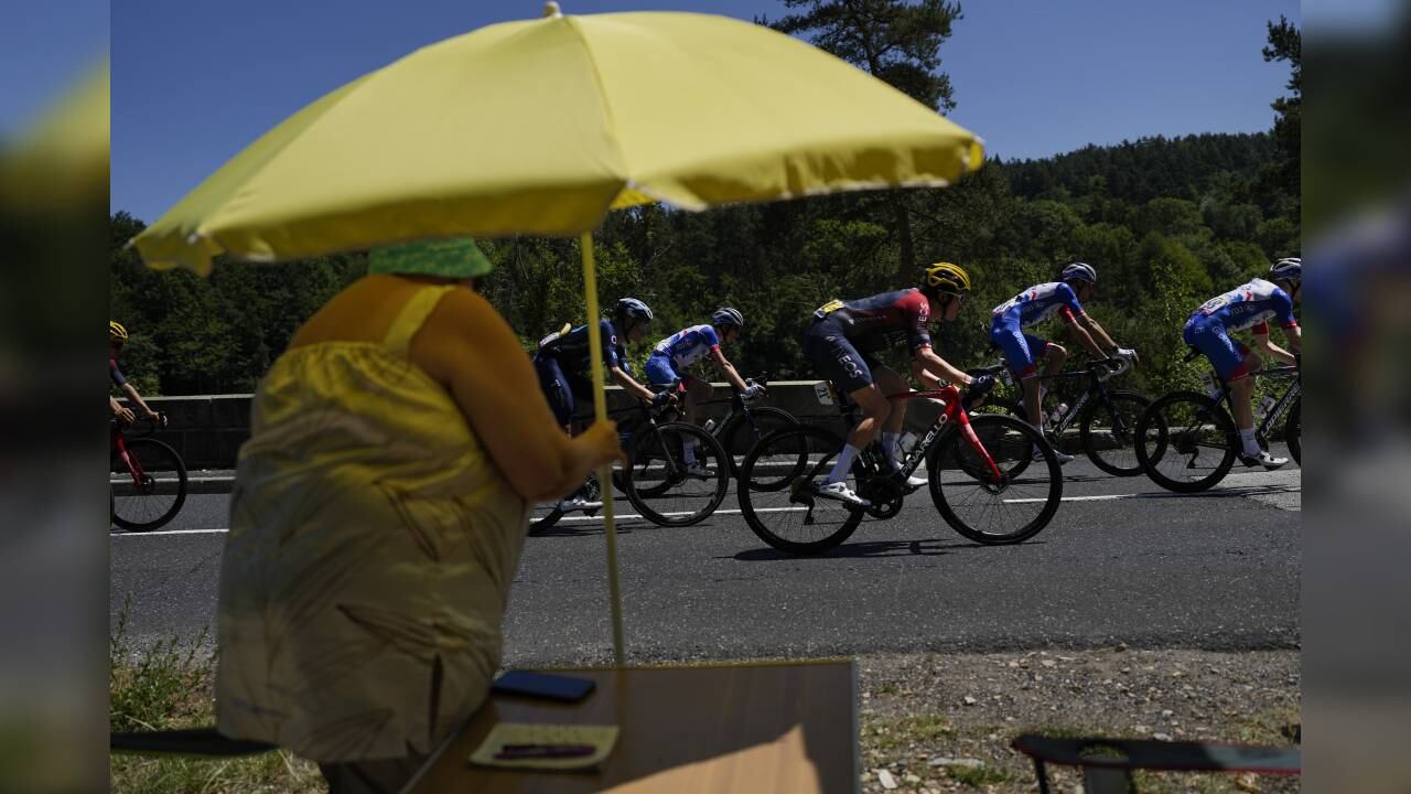 Una mujer observa el paso del británico Geraint Thomas, con casco amarillo, y otros corredores del pelotón del Tour de Francia. Foto: AP/Thibault Camus.