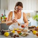 Mature woman pouring honey in ginger and lemon hot tea cup