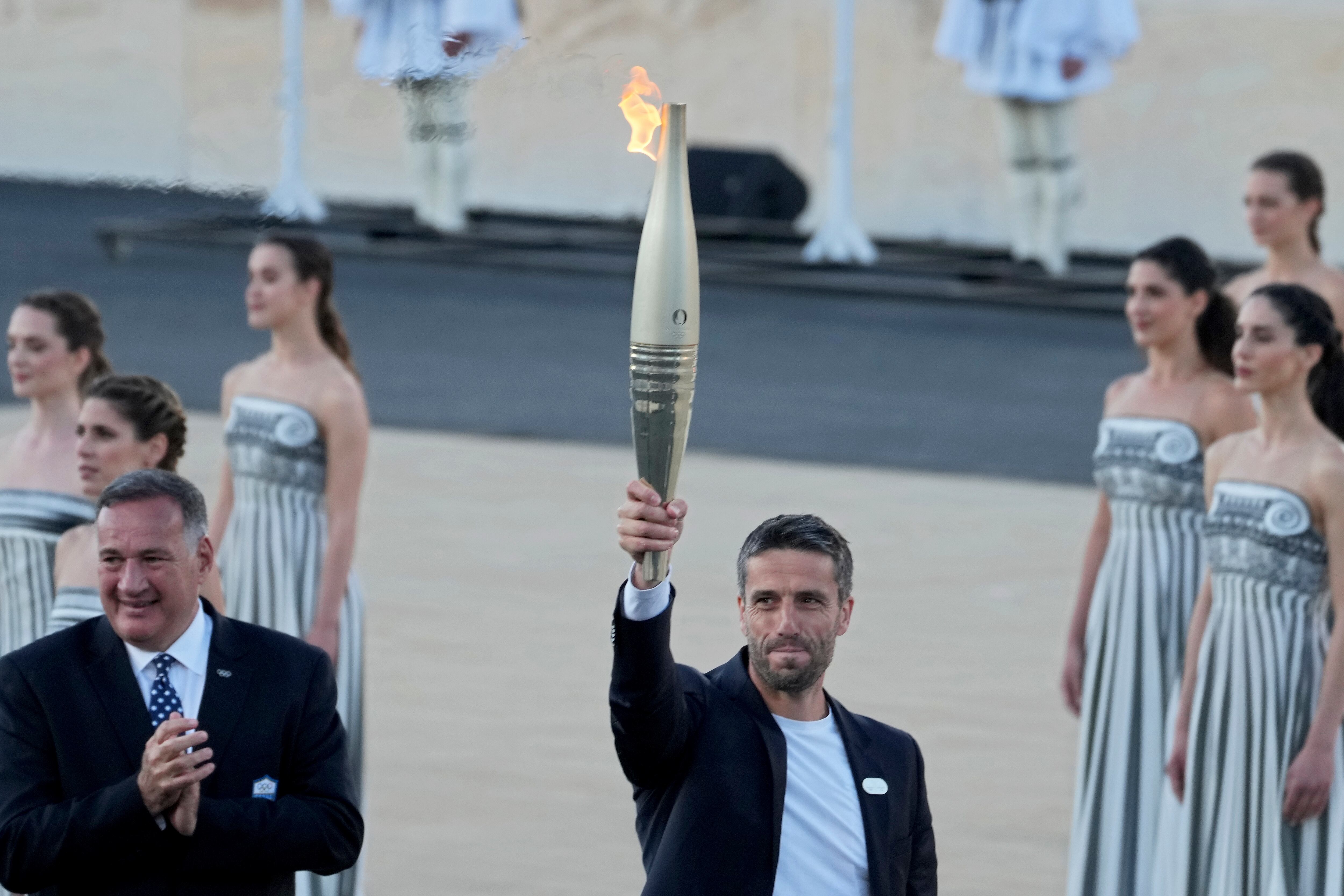 Tony Estanguet, presidente de París 2024, a la derecha, sostiene la llama olímpica mientras Spyros Capralos, jefe del Comité Olímpico de Grecia, a la izquierda, aplaude durante la ceremonia de entrega de la llama en el estadio Panatenaico, donde se celebraron los primeros juegos modernos en 1896, en Atenas, el viernes. , 26 de abril de 2024.