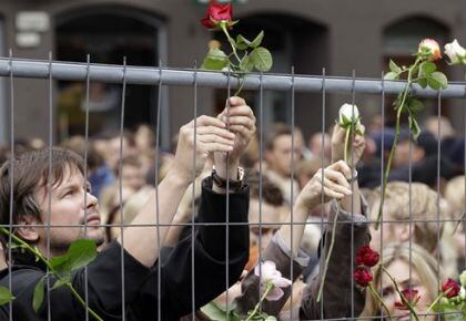 Un hombre fija una rosa a una valla en memoria de las víctimas del atentato de Oslo y la masacre de Utoya. 