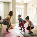 Madre haciendo ejercicio en casa con hijas pequeñas