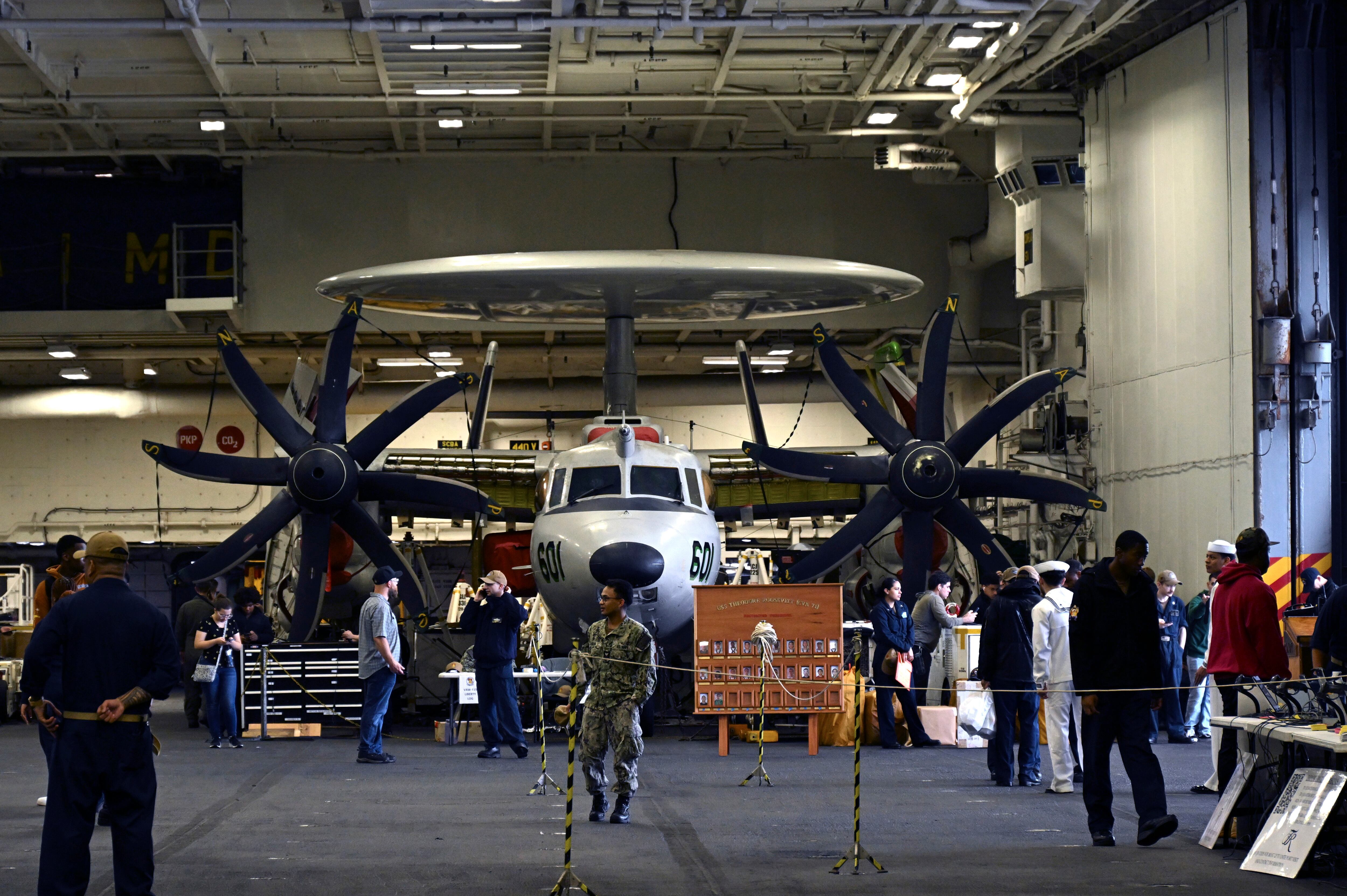 Los miembros de la tripulación caminan en avión en el hangar del Theodore Roosevelt (CVN 71), un portaaviones de propulsión nuclear, anclado en la Base Naval de Busan, Corea del Sur, el sábado 22 de junio de 2024.