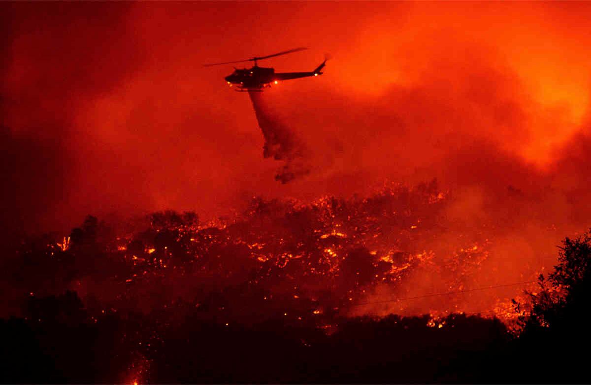 Un helicóptero arroja agua sobre un incendio cerca a la autopista 154 en el Bosque Nacional Los Padres, California, el martes 26 de noviembre de 2019. (Foto: AP / Noah Berger)