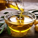 Botella vertiendo aceite de oliva virgen en un recipiente de cerca