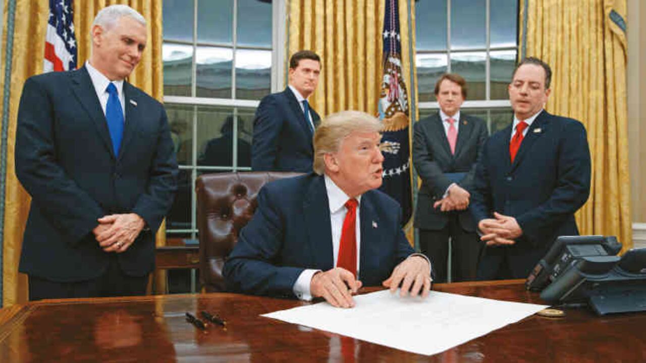 Donald Trump en el Despacho Oval de la Casa Blanca rodeado por su vicepresidente, Mike Pence, y algunos de sus asesores.