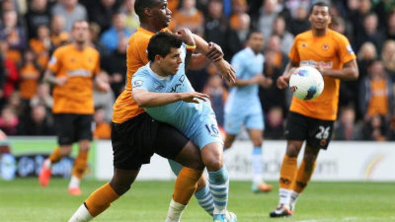l jugador argentino del Manchester City, Sergio Agüero (d) lucha por el balón con Sebastian Bassong (i) del Wolverhampton Wanderers durante el partido de la Premier League inglesa que ambos equipos disputaron.