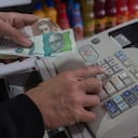 Colombian money, pesos, in hand in a cash register . concept of economics