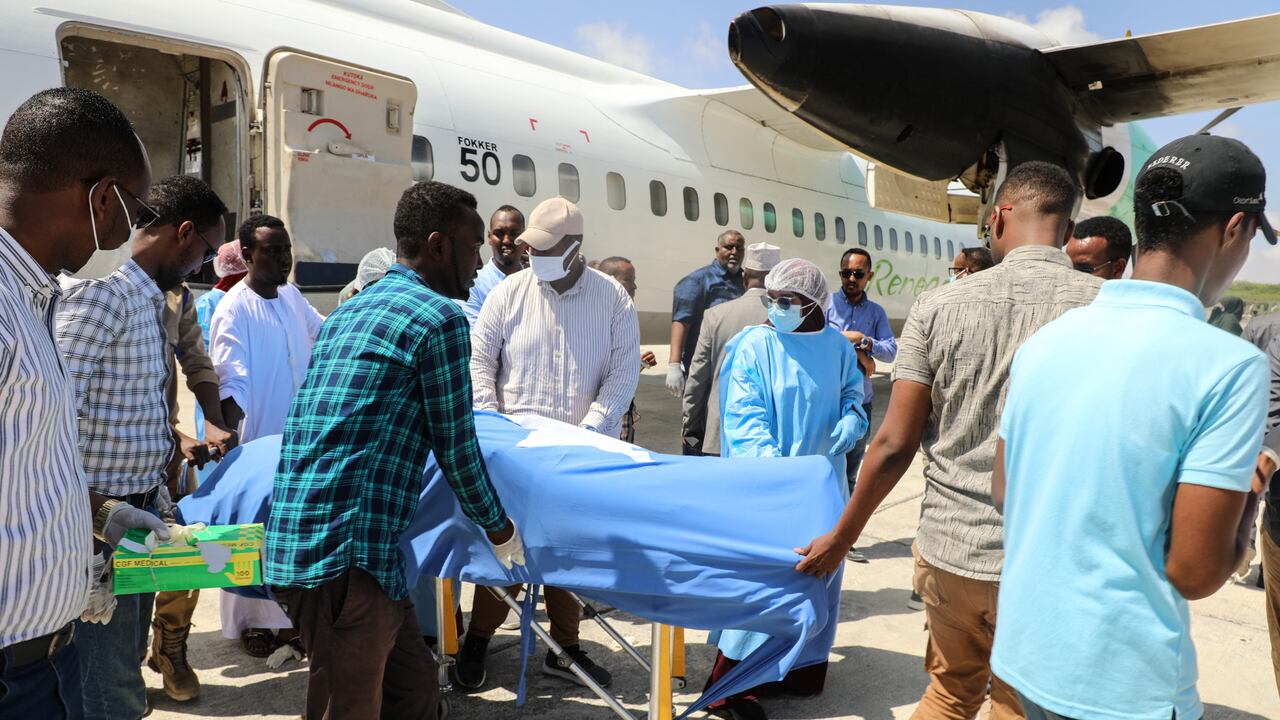 La gente descarga el cuerpo de la legisladora local después de que muriera en un atentado suicida con bomba en Beledweyne, en el Aeropuerto Internacional Aden Adde en Mogadishu, Somalia, el 24 de marzo de 2022. - (Foto de Hassan Ali ELMI / AFP)