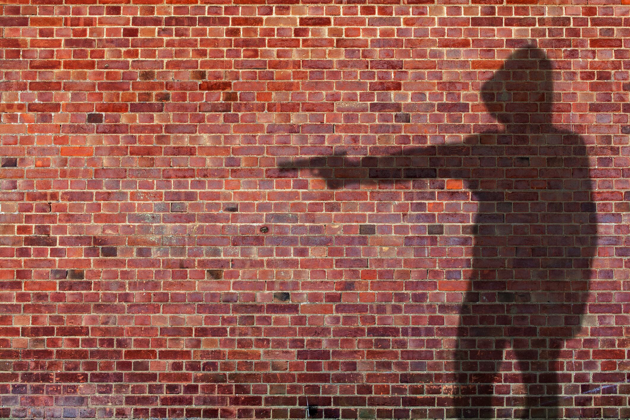 Shadow on wall of person holing gun