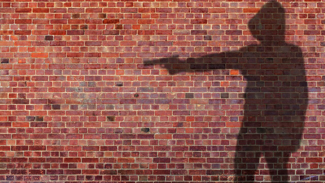Shadow on wall of person holing gun