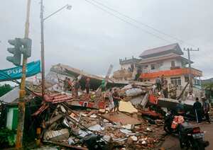 Residents inspect earthquake-damaged buildings in Mamuju, West Sulawesi, Indonesia, Friday, Jan. 15, 2021. A strong inland and shallow earthquake hit eastern Indonesia early Friday causing people to panic in parts of the country's Sulawesi island and run to higher ground. (AP Photo/Rudy Akdyaksyah)