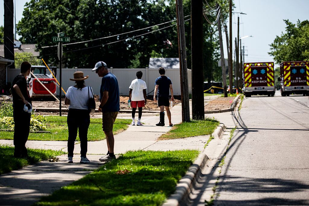 WAYNE, MICHIGAN - JUNE 22: Residents and other people look on as police and emergency response vehicles line the street near the scene of a shooting at CrossPointe Community Church on June 22, 2025 in Wayne, Michigan. Police report that a shooting suspect was shot dead by a security guard after opening fire at the church leaving one person injured. (Photo by Emily Elconin/Getty Images)
