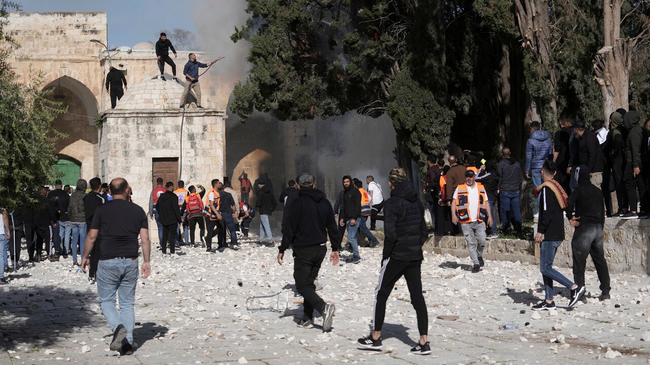 Los palestinos trabajan para extinguir un árbol que se incendió cuando la policía israelí se enfrentó a los manifestantes en el complejo de la mezquita de Al Aqsa, en la Ciudad Vieja de Jerusalén, el viernes 22 de abril de 2022.