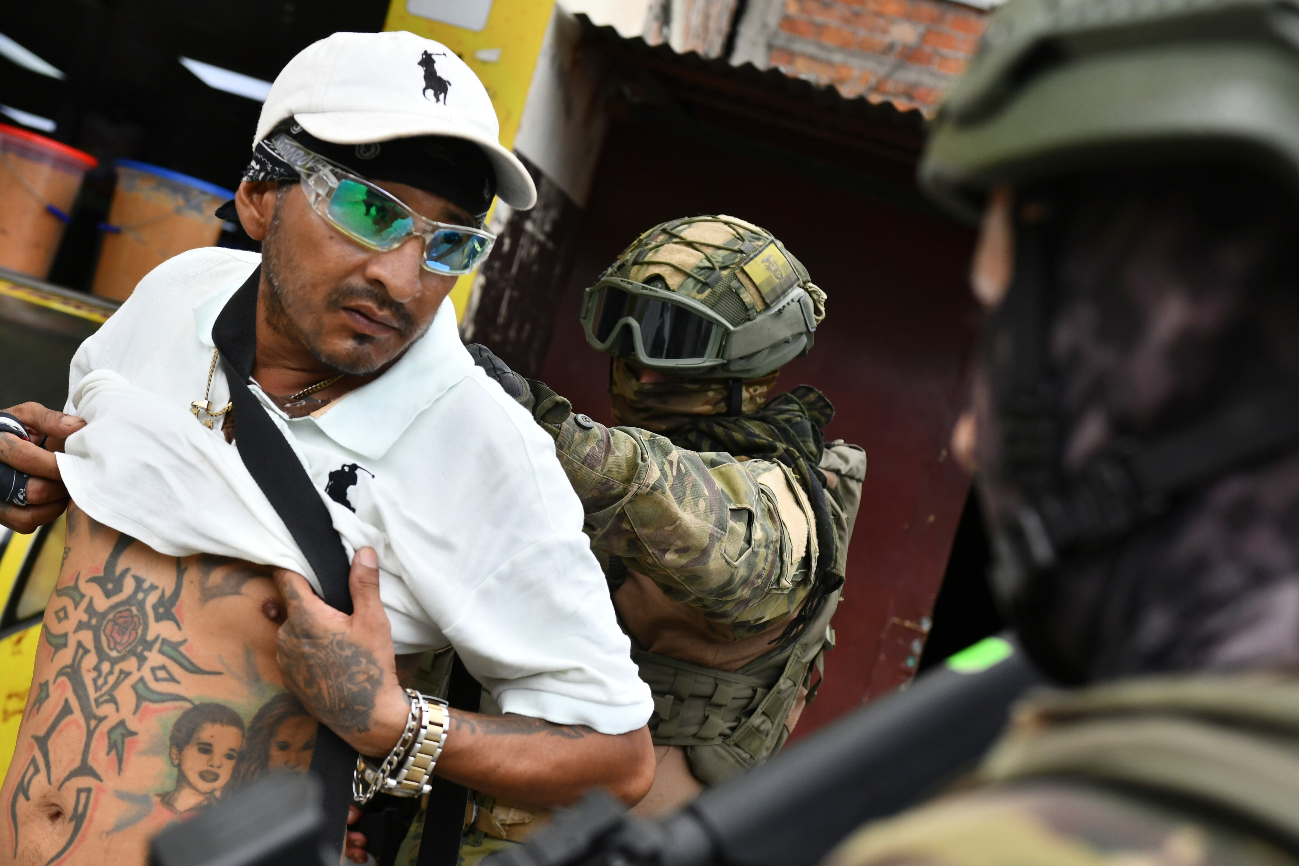 Un soldado examina la espalda de un hombre buscando tatuajes relacionados con pandillas, durante una operación de detención y cacheo en Portoviejo, Ecuador, el jueves 11 de enero de 2024.