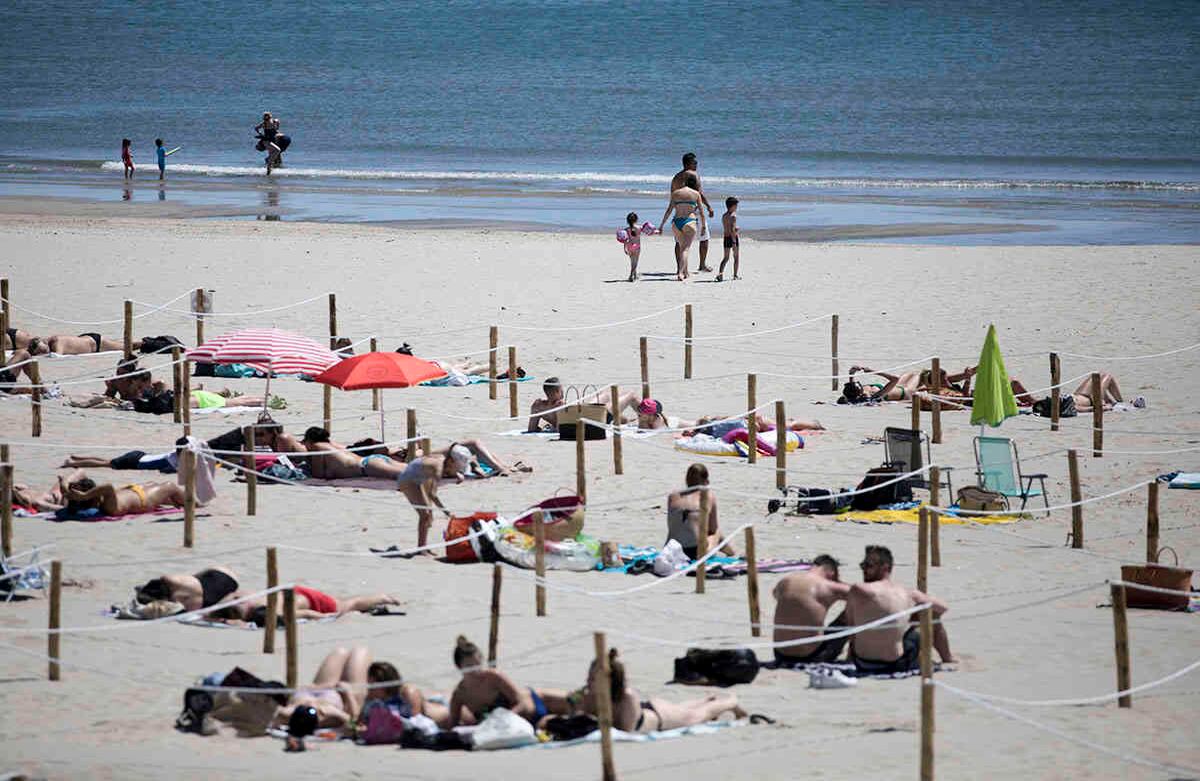 Los que toman el sol yacen en un área marcada por cordones de cuerdas y estacas de madera para hacer cumplir las normas de distanciamiento, en La Grande Motte, sur de Francia. Imagen del 24 de mayo. Las familias acudieron a la playa, tratando de mantener distancia entre sí. Foto: Daniel Cole/ AP