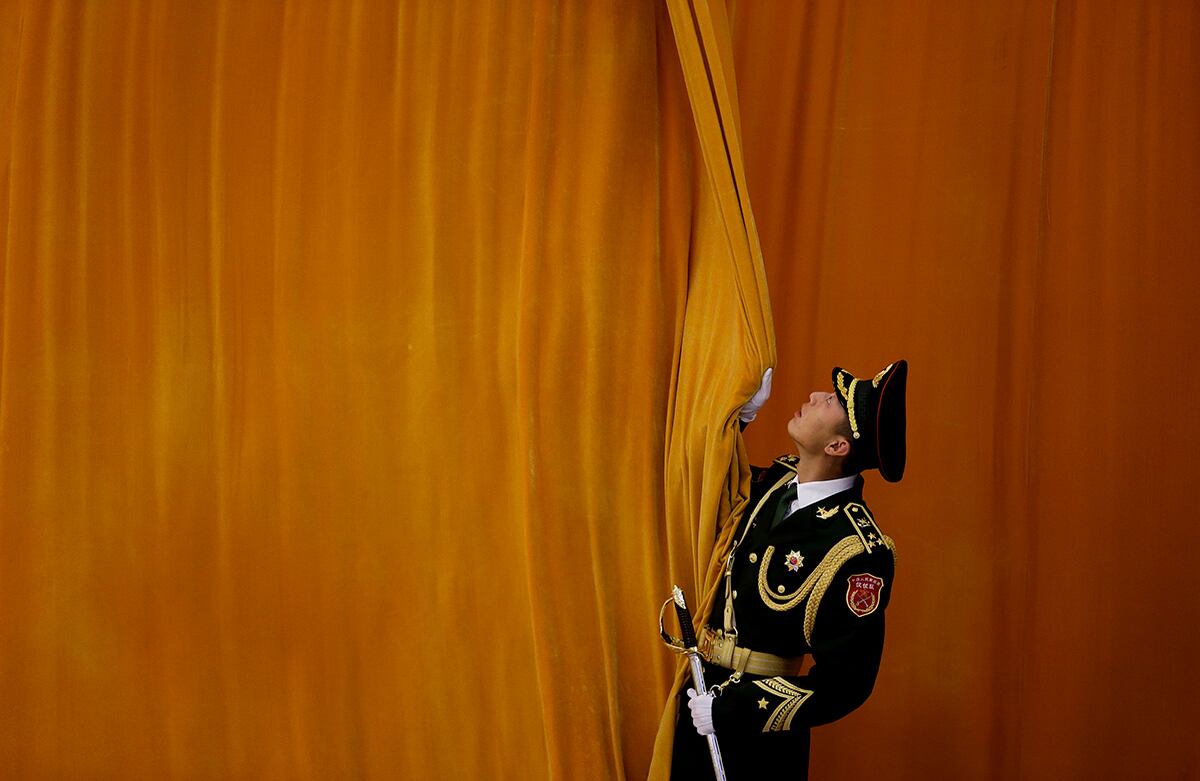 Un soldado chino cierra una cortina mientras se realizan preparaciones para una ceremonia de bienvenida por la visita del presidente mexicano Enrique Peña Nieto al país de oriente. (AP)